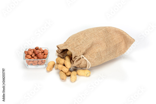 Peanuts. Jute burlap sack full of peanuts and glass bowl with peeled kernels, isolated on white background.