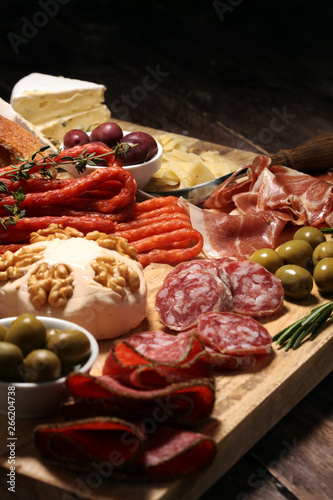 Cutting board with prosciutto, salami, cheese,bread and olives on dark wooden background