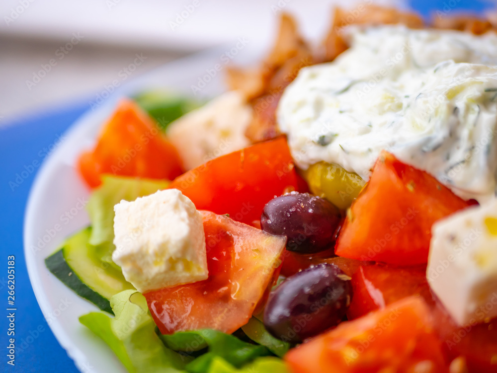 Close up of tomatoes, olives, feta cheese and slices of cucumbers from a famous Greek salad, against a blurred background Close up of tomatoes, olives, feta cheese and slices of cucumbers from a famous Greek salad, against a blurred background