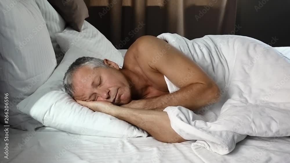 An elderly person sleeps in the early morning and smiles in his sleep, lying in bed. An elderly person sleeps in the early morning and smiles in his sleep, lying in bed.