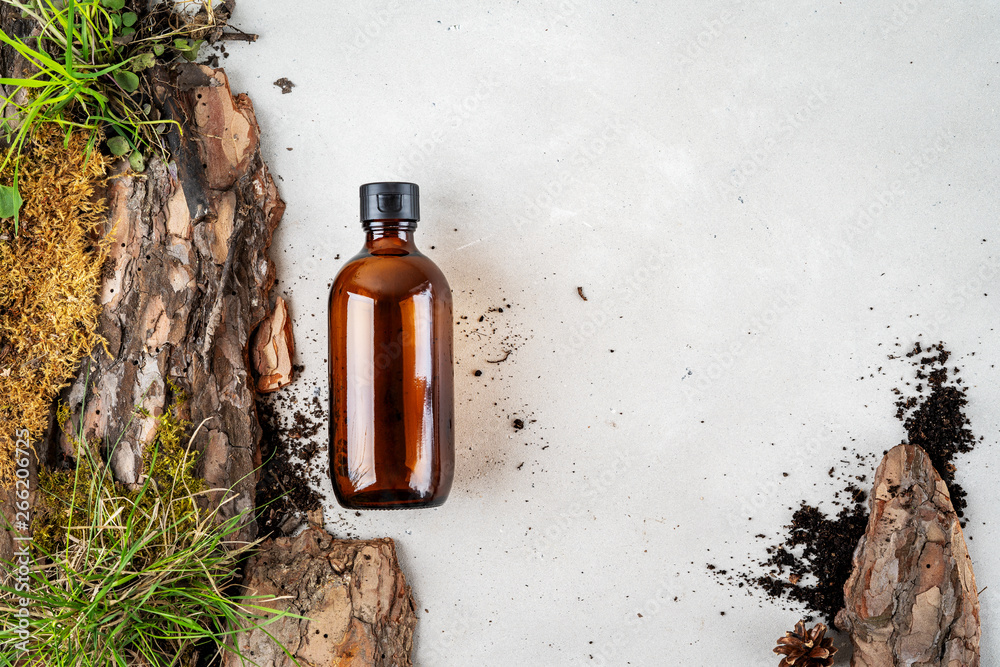 Environmentally clear nature concept background. Composition with glass bottle of shampoo over bark tree, moss and earth with grass for organic cosmetic products on white with copy space. Environmentally clear nature concept background. Composition with glass bottle of shampoo over bark tree, moss and earth with grass for organic cosmetic products on white with copy space.