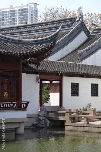 Ancient Chinese houses on the background of a modern building. Ordinary cityscape in China.