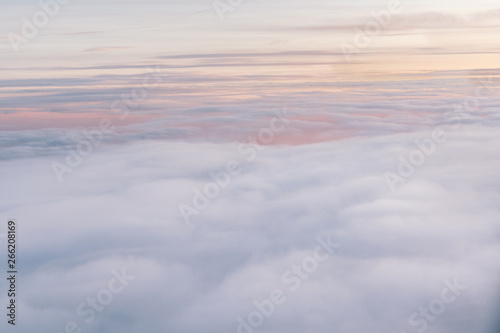 The view from the airplane s porthole on the sky is orange-pink in color with air clouds