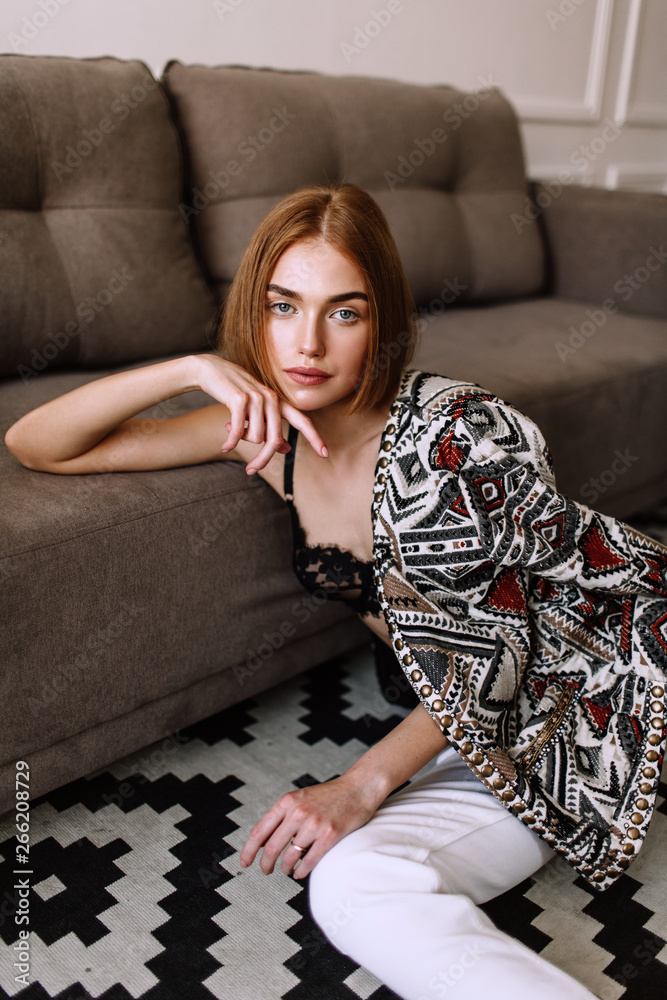 Obraz premium Beautiful sweet girl professionally posing on camera. Golden stylish model with short red hair, plump lips, casual clothing, costume, outfit, bra. Model test, clothing advertising
