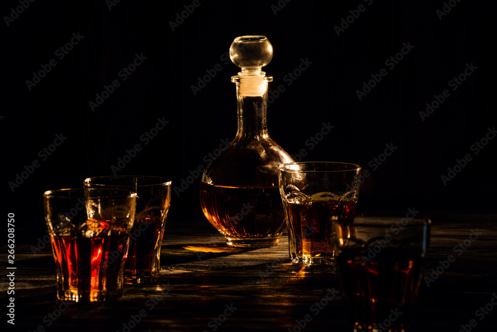 cognac in glasses and decanter, an exquisite alcoholic drink for men, shot in a dark light key cognac in glasses and decanter, an exquisite alcoholic drink for men, shot in a dark light key