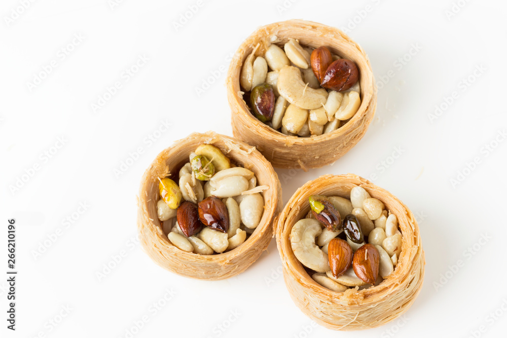 Traditional arabic dessert Kunafa with honey and nuts, on a white background, selective focus Traditional arabic dessert Kunafa with honey and nuts, on a white background, selective focus
