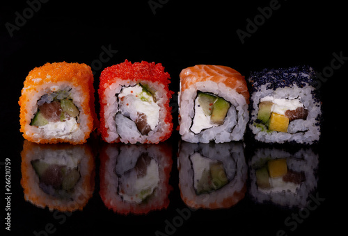 Japanese food,close-up  fresh sushi set of  four diferent types on black background with reflection