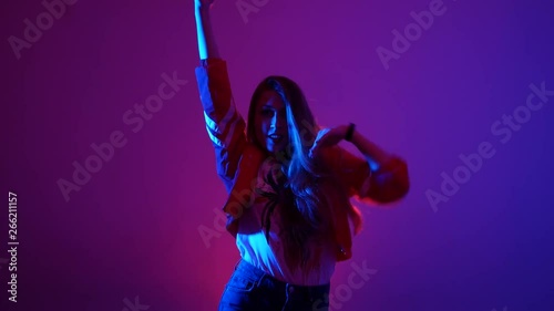 young beautiful woman dancing hip-hop, street dancing in the studio on a purple background, isolated