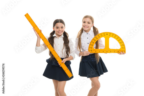 Pupils cute girls with big rulers. Favorite school subject. Education and school concept. School students learning geometry. Kids school uniform isolated white. STEM concept. Draw geometric figures photo