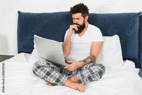 Just woke up and already at work. Man surfing internet or work online. Hipster bearded guy pajamas freelance worker. Remote work concept. Social networks internet addiction. Online shopping