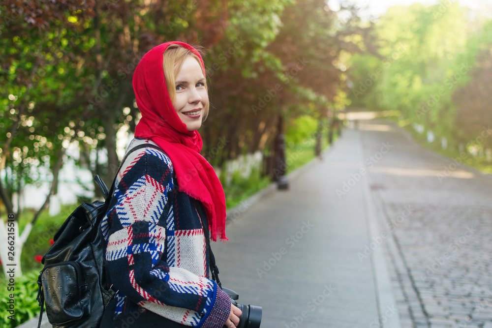 A middle aged woman with a red veil on her head in a park in summer. A middle aged woman with a red veil on her head in a park in summer.