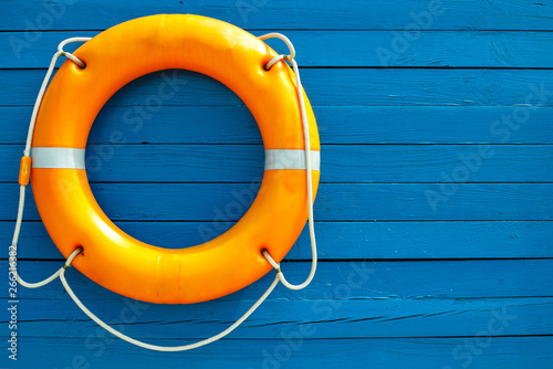 Orange lifebuoy on blue wooden wall.