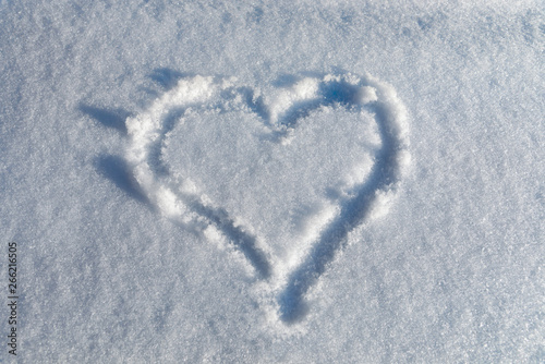 drawing a heart in the snow on a sunny day