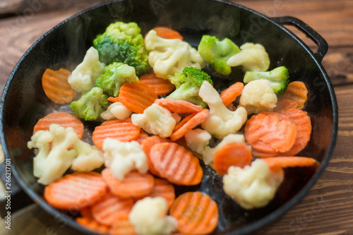 Fresh frozen chopped vegetables - cabbage, carrots in a frying pan. Cooking fried vegetables.