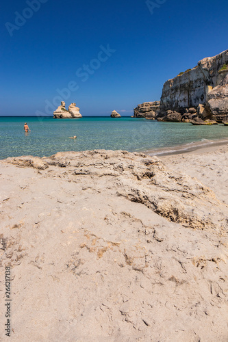 Fototapeta Naklejka Na Ścianę i Meble -  The bay of Torre dell'Orso, with its high cliffs, in Salento, Puglia. Fine white sand beach. The stacks called the Two Sisters. Beautiful girl bathing and playing in the turquoise sea with her dog