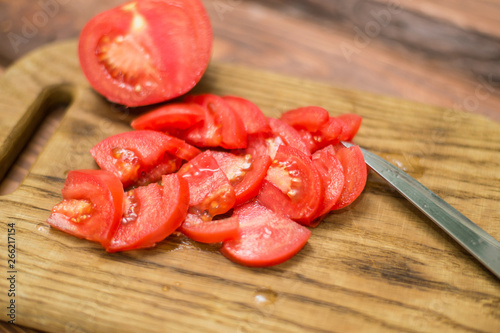 Sliced red tomato on a chopping board with a knife.