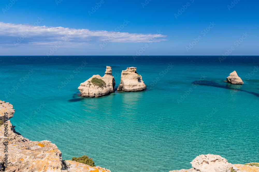 The bay of Torre dell'Orso, with its high cliffs, in Salento, Puglia, Italy. Turquoise sea and blue sky, sunny day in summer. The stacks called the Two Sisters, immersed in the sea. The bay of Torre dell'Orso, with its high cliffs, in Salento, Puglia, Italy. Turquoise sea and blue sky, sunny day in summer. The stacks called the Two Sisters, immersed in the sea.