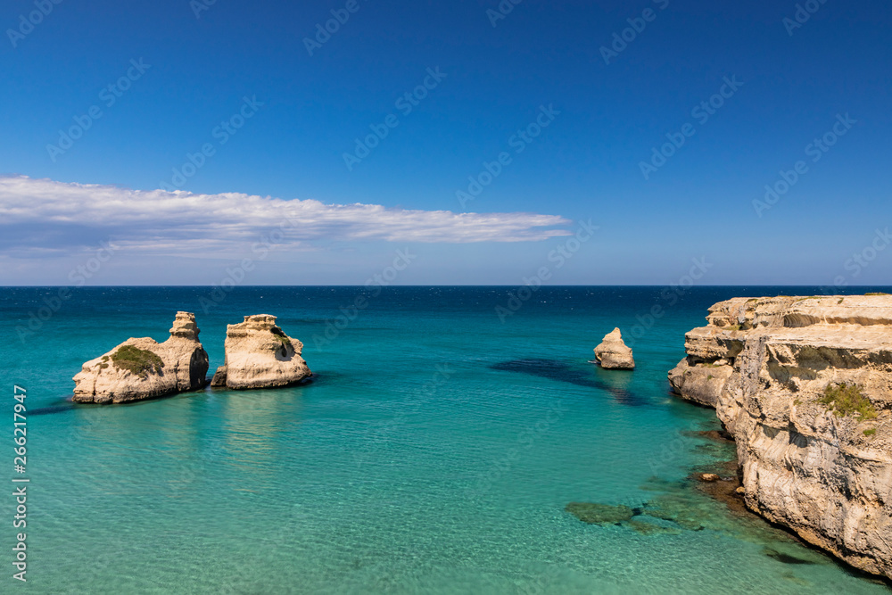 The bay of Torre dell'Orso, with its high cliffs, in Salento, Puglia, Italy. Turquoise sea and blue sky, sunny day in summer. The stacks called the Two Sisters, immersed in the sea.