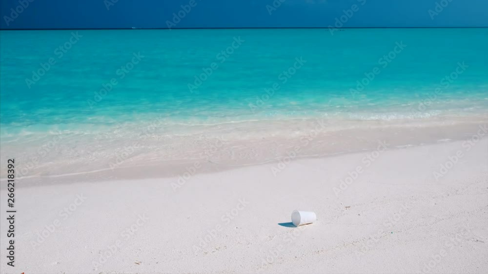 White plastic cap lies on the perfect sandy beach. Plastic trash pollutes the pristine sea and the tropical beach White plastic cap lies on the perfect sandy beach. Plastic trash pollutes the pristine sea and the tropical beach