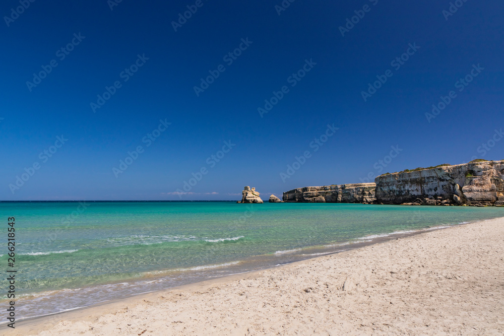 The bay of Torre dell'Orso, with its high cliffs, in Salento, Puglia, Italy. Turquoise sea and blue sky, sunny day in summer. Fine white sand beach. The stacks called the Two Sisters.