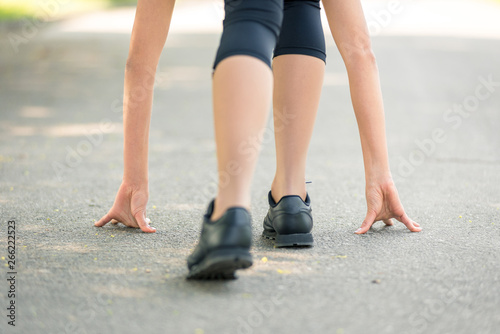 Female legs and hands put on the asphalt close-up, symbol of the start before the run, strong personality and marathon run