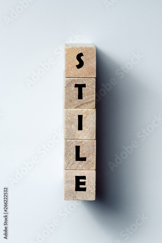 a line of wooden cubes with the word "style", on an uneven white background. Vertical frame