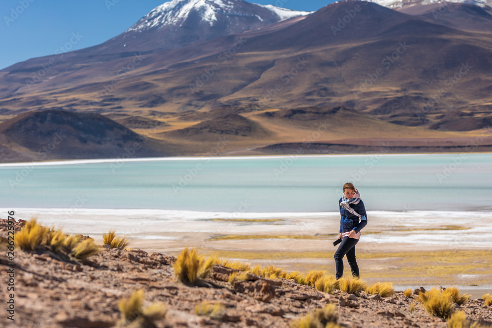 Women hiker looking at views in an amazing wilderness environment at Atacama Desert Andes mountains lagoons at Tuyajto Lagoon. A woman cut out silhouette over the awe Andean Altiplano scenery