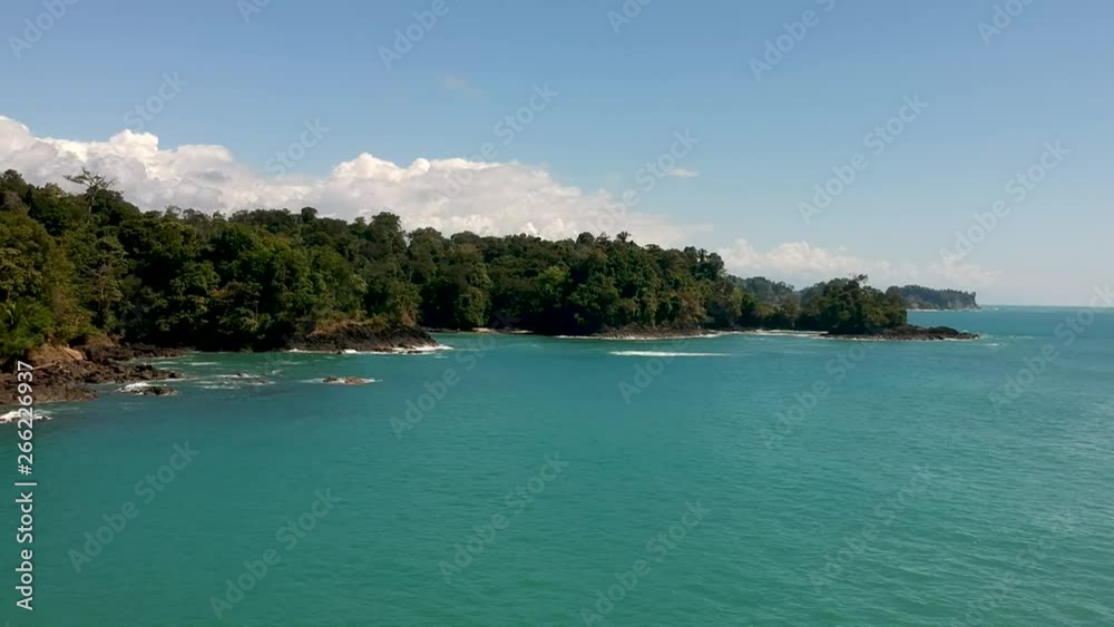 Aerial view of tropical turquoise sea water, jungle hills and blue sky background in Manuel Antonio national park, Costa Rica. Panning left shot. Aerial view of tropical turquoise sea water, jungle hills and blue sky background in Manuel Antonio national park, Costa Rica. Panning left shot.