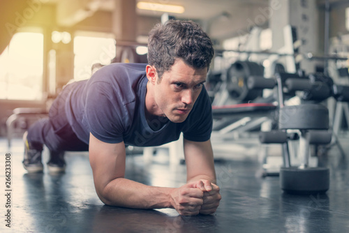 Handsome man and strong guy doing plank position exercise in fitness gym