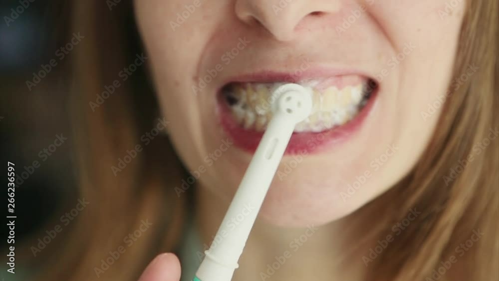 the face of a girl who brushes her teeth with an electric brush close-up the face of a girl who brushes her teeth with an electric brush close-up