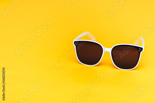 white sunglasses on bright yellow background, copyspace, summer is coming concept