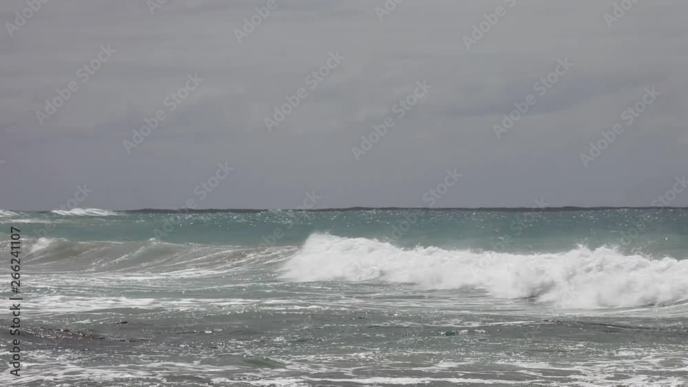 Distant waves surging rolling in under overcast sky above. Distant waves surging rolling in under overcast sky above.