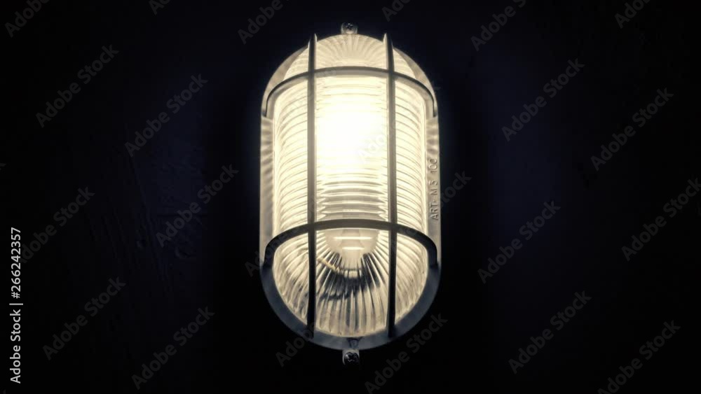 A scary flickering light lamp inside a basement, turning on and slightly off because of the unstable electrical current (or a paranormal phenomenon).