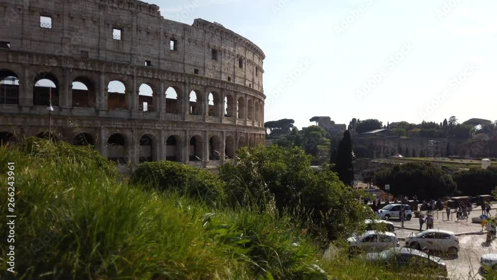 The colosseum from an higher side on a sunny spring day. Time-lapse,1o minutes long. Cars are passing by. People are walking on the sidewalk. motion lapse from left to right.