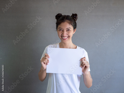 Close up portrait of positive laughing woman smiling and holding white big mockup poster isolated on gray background