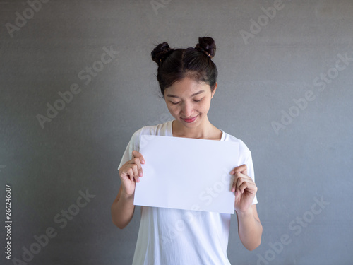 Close up portrait of positive laughing woman smiling and holding white big mockup poster isolated on gray background