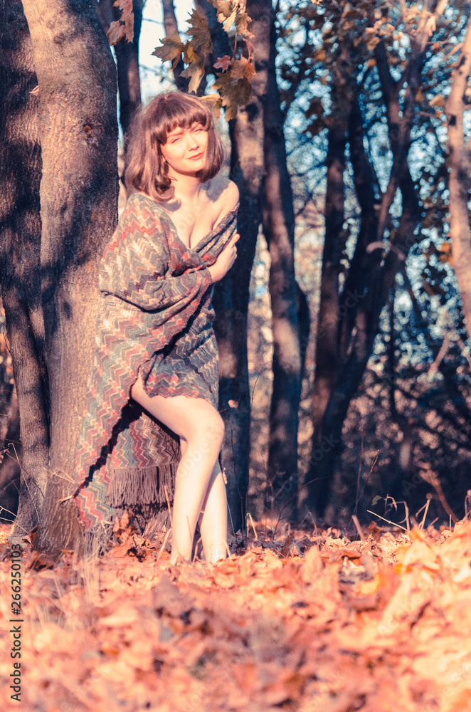 Pretty Young Woman Sitting on Grassy Ground with Dried Leaves Listening Music Ipod Headset. Looking at Camera. Isolated Nature Background. Pretty Young Woman Sitting on Grassy Ground with Dried Leaves Listening Music Ipod Headset. Looking at Camera. Isolated Nature Background.