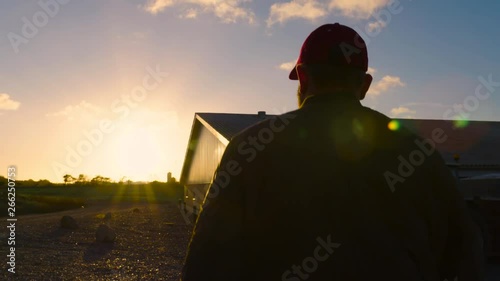 Farmer walking outside in grass and farm in sunshine photo