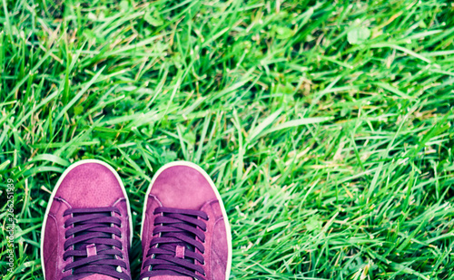 Pair of sport shoes of pink suede on the grass in park.