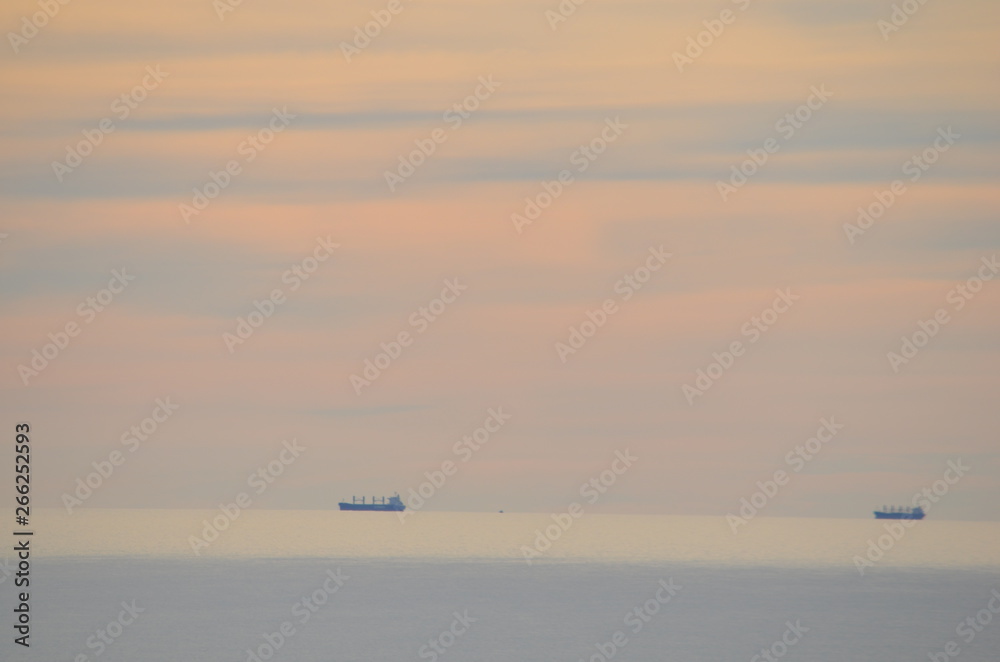 ocean sunset scene with orange and yellow clouds with a burnished sky and calm ocean with cargo ships off Glenelg South Australia ocean sunset scene with orange and yellow clouds with a burnished sky and calm ocean with cargo ships off Glenelg South Australia