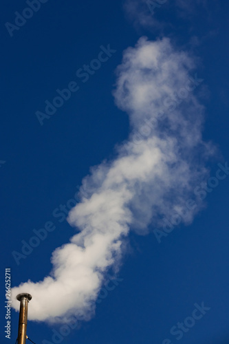 white smoke, steam from the pipe against the blue sky