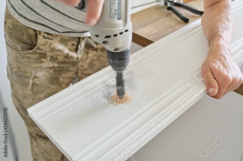 Close-up of carpenters hand using professional woodworking electric tools when working with wood. Male carving hole in wooden panel board, carpentry, woodwork, profession, people