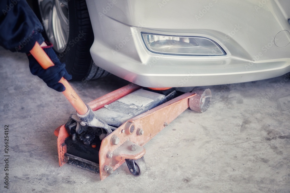 Car care , The car mechanic is lifting the car with the hydraulic Floor Jack. (Spot focus) Car care , The car mechanic is lifting the car with the hydraulic Floor Jack. (Spot focus)