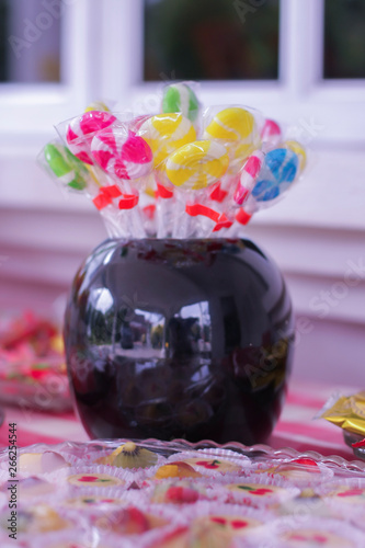 Colorful candy sweets inside black jar on the table.