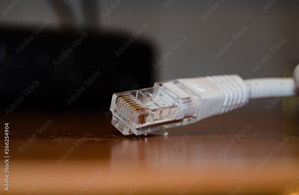 Close up of internet cable on wooden table with modem in the background Close up of internet cable on wooden table with modem in the background