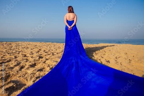 Beautiful woman standing on a cliff over blue sky and Goa sea. Brunette girl
