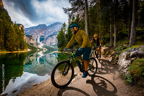 Couple cycling on electric bike, rides mountain trail. Woman and Man riding on bikes in Dolomites mountains landscape. Cycling e-mtb enduro trail track. Outdoor sport activity. © Gorilla