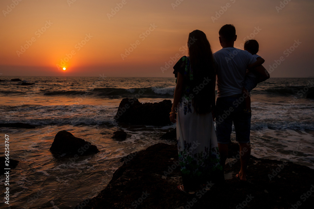 Happy family holding hands on beach and watching the sunset sunrice at Goa India ocean