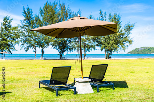 Umbrella and chair on the green grass nearly sea beach © siraphol