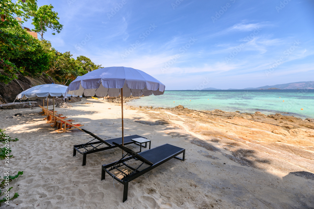 Umbrella with wooden sunbed on the white beach at tropical sea Umbrella with wooden sunbed on the white beach at tropical sea